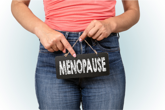Person holding a chalkboard sign that reads "MENOPAUSE" near their waist.