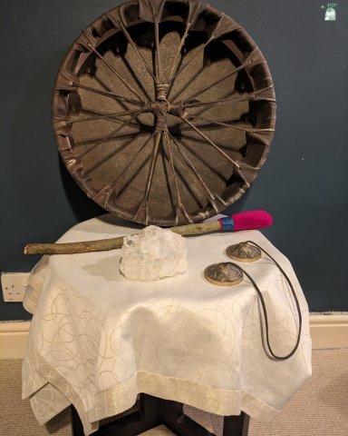 A decorative wheel and various tools displayed on a table with a lace cloth.